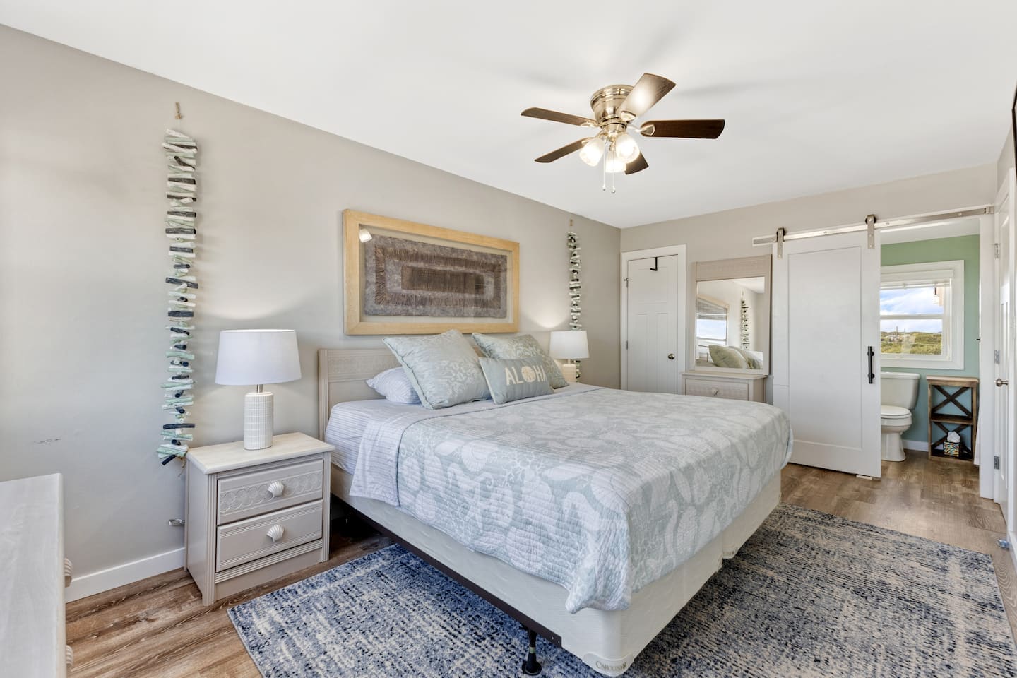 Master bedroom with seashell bedding and barn-door bath