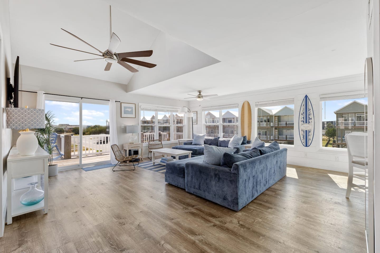 Open living room with dusty-blue sectional and surfboard decor