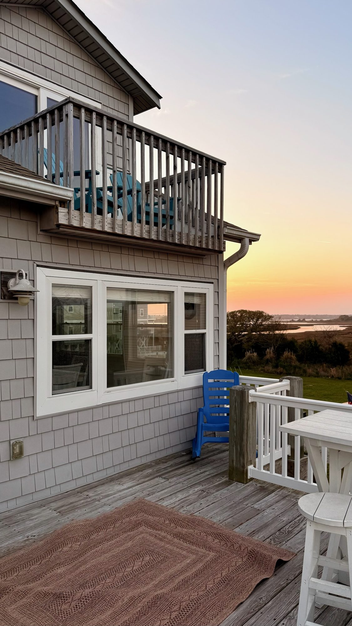 Deck at sunset with a blue chair and the sound beyond