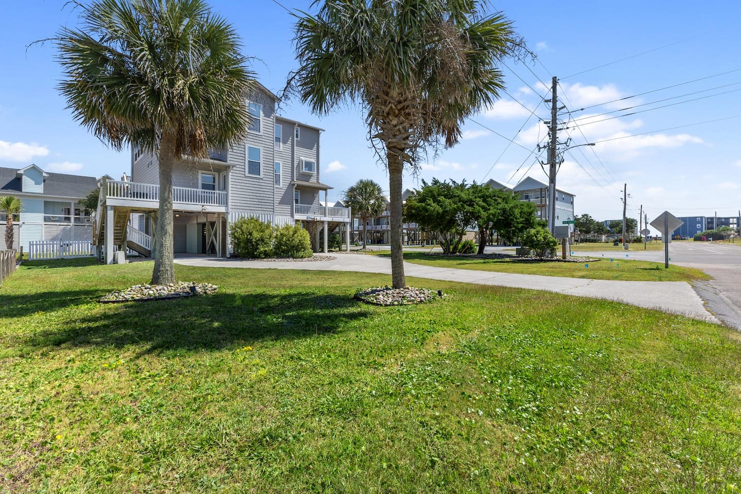 Front exterior with palm trees, lawn, and white railings
