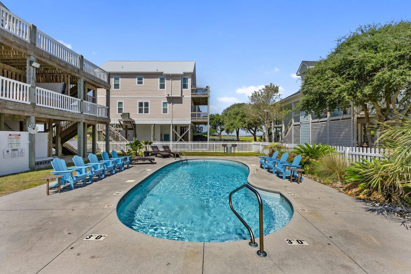 Kidney-shaped pool with blue Adirondack chairs