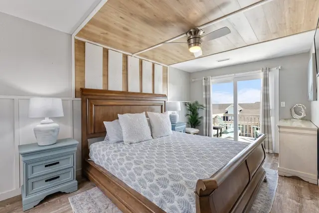 Primary bedroom with balcony and seafoam nightstands