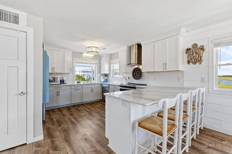 Coastal kitchen with white and gray cabinets and a marsh view, ready for a holiday dinner at Topsail Paradise
